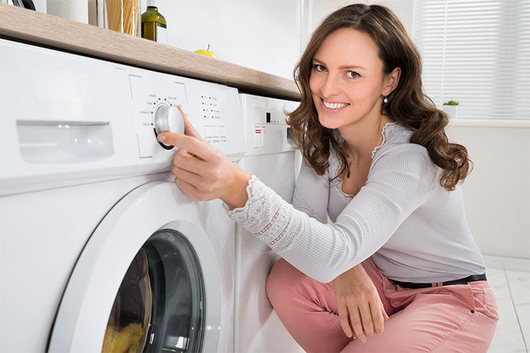 Frau bedient Waschmaschine