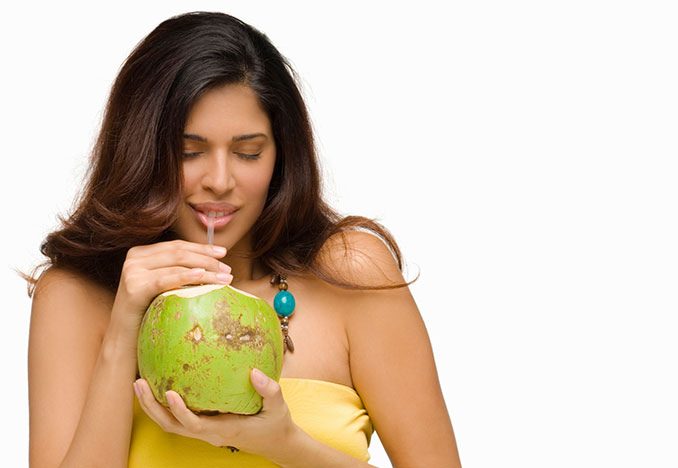 Frau trinkt aus Kokosnuss