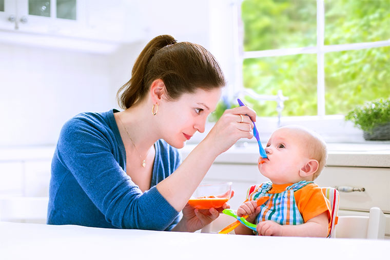 Mutter füttert Baby mit Brei